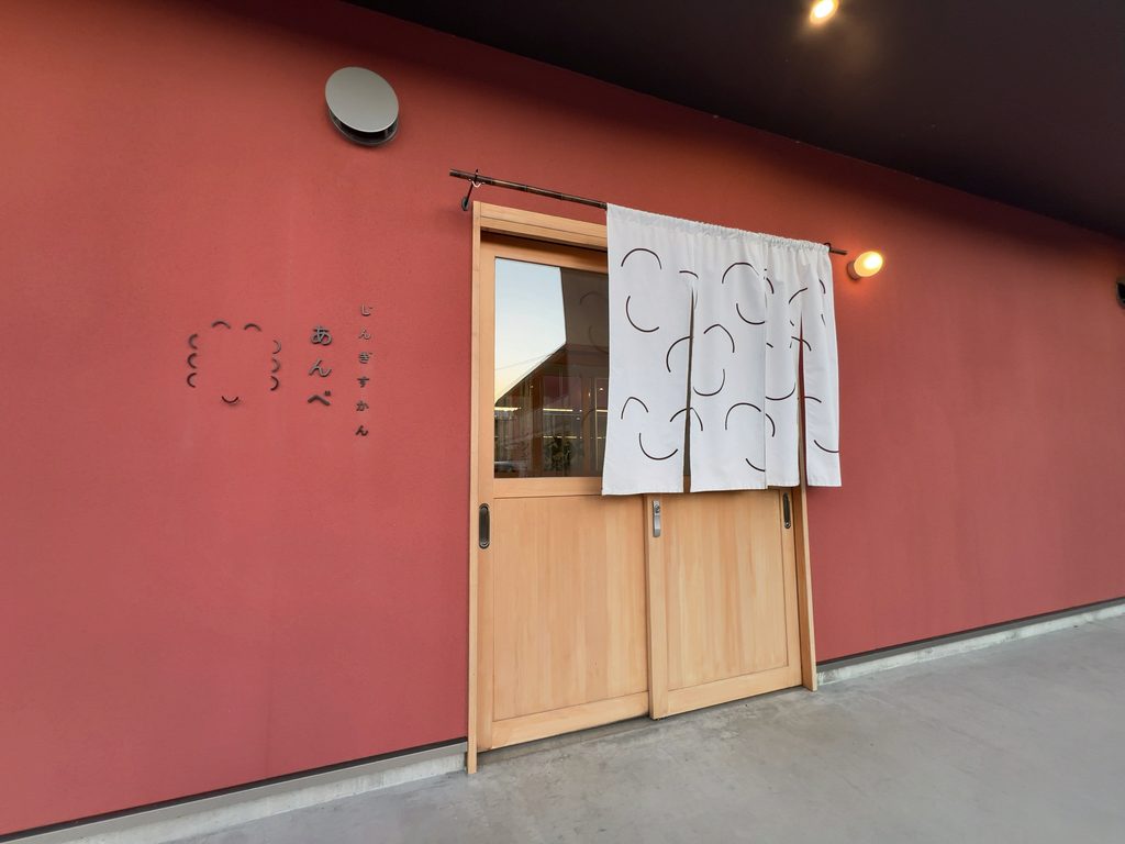 赤い外壁と白い暖簾が目を引く「じんぎすかん あんべ」の店舗入口