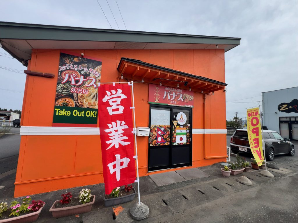 オレンジ色の外壁に「パナス 水沢店」の看板と「営業中」ののぼりが立つ店舗正面