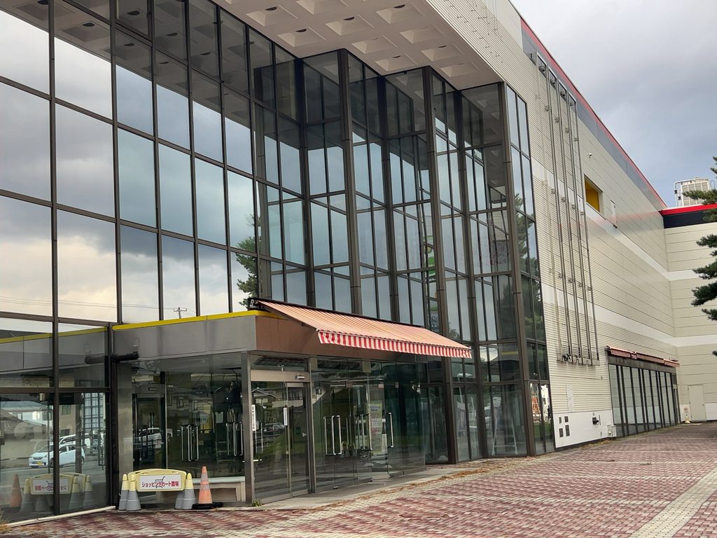 赤と白のストライプの庇とショッピングカート置場の看板がある店舗入口