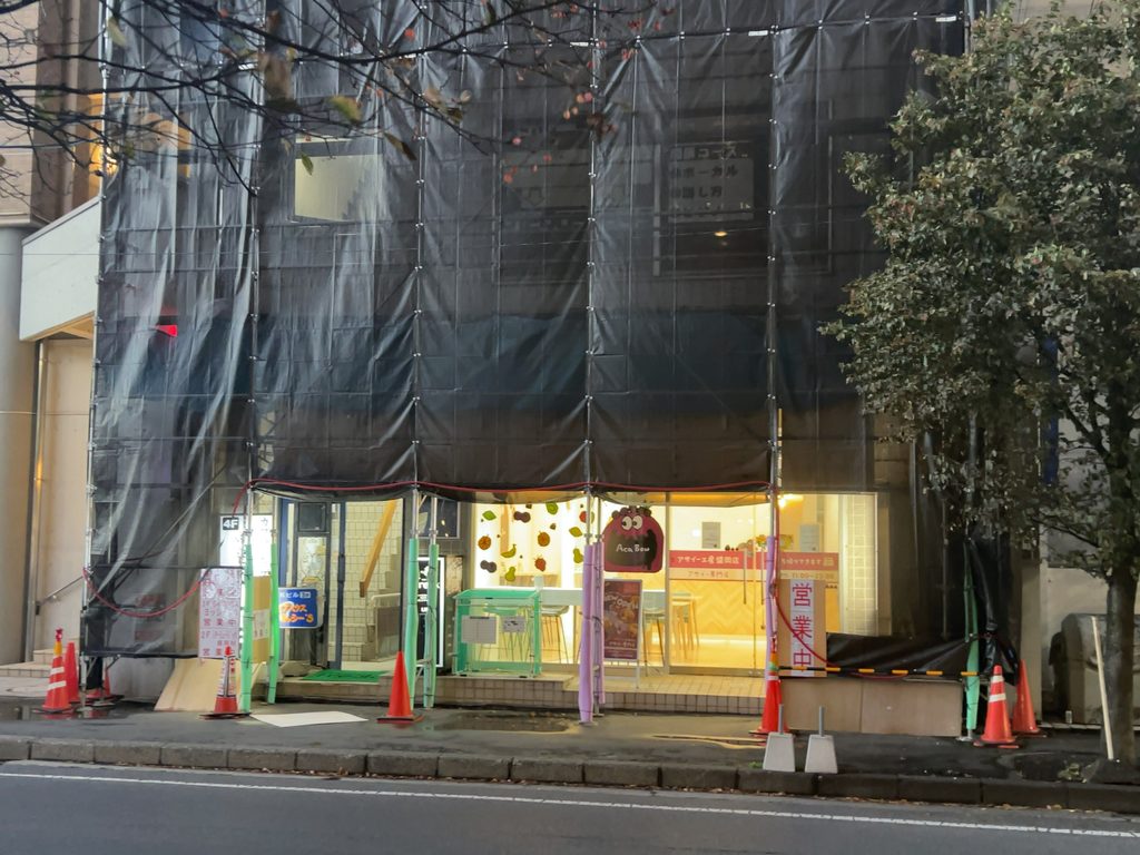 足場と黒い保護シートで覆われた建物1階にある「アサイー工房 盛岡店」の店舗外観