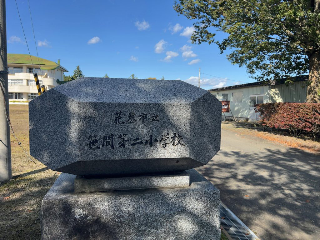 「花巻市立笹間第二小学校」と刻まれた校名碑と奥に見える校舎
