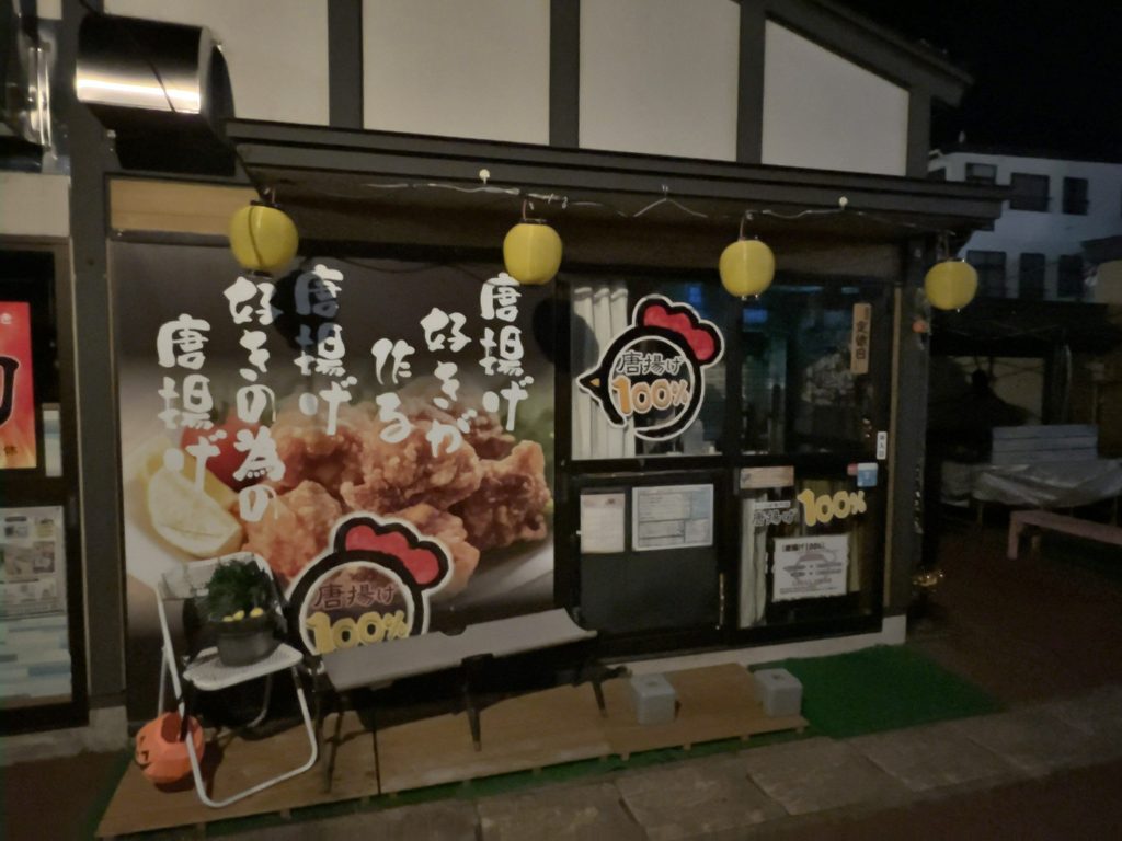 鶏のマークのロゴやベンチが設置された「唐揚げ100%」の店舗外観
