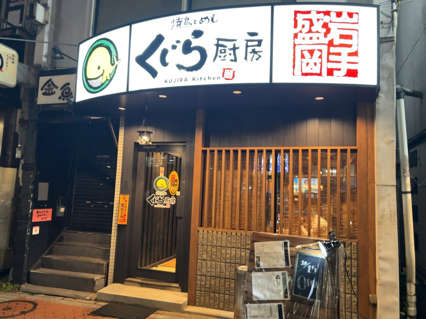 焼鳥とめし くじら厨房の夜の外観。入口横の黒板に「10/15 OPEN」と書かれている