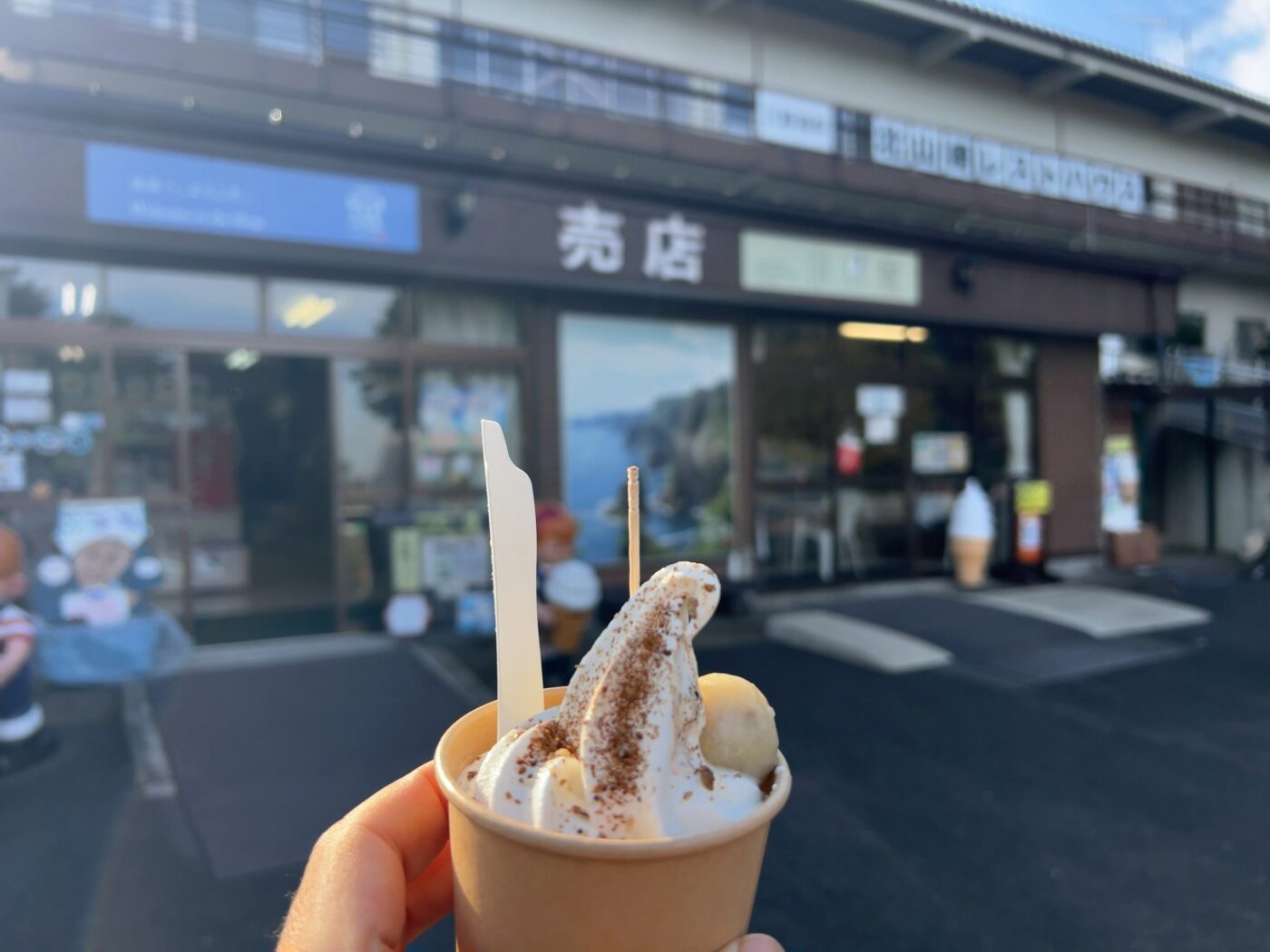 北山崎レストハウスの売店の前でまめぶソフトを持っているところ