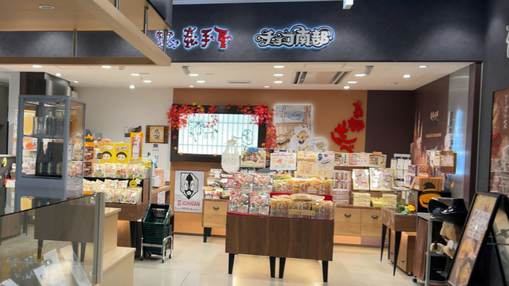 赤い電飾看板「巖手屋」と「チョコ南部」の看板が掲げられた「南部せんべい乃 巖手屋 monaka店」の店内